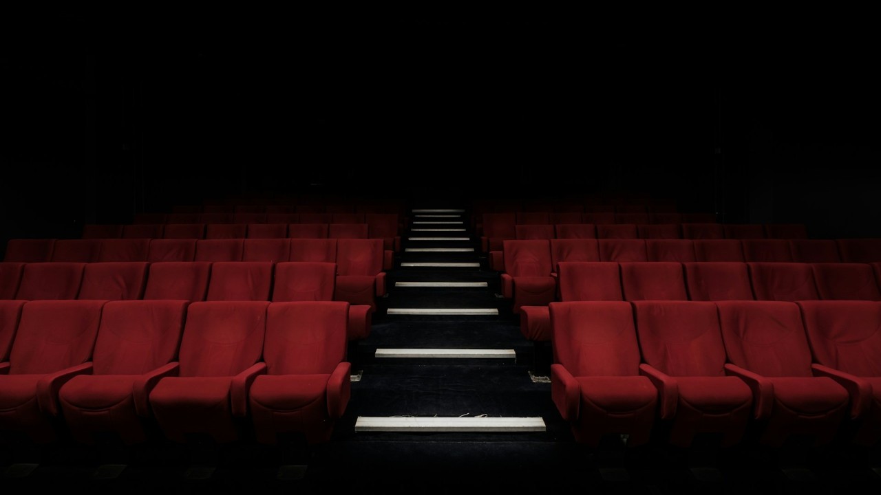 Empty cinema seats facing a lit projection screen
